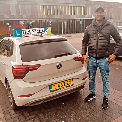Geslaagde leerling bij de lesauto met het daklichtbord